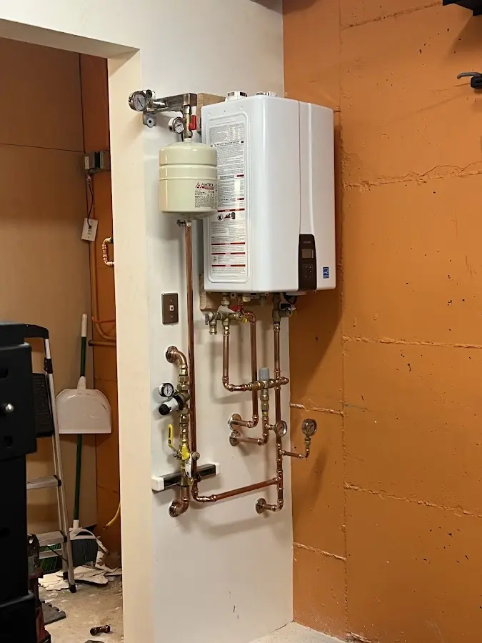 Plumbing technician inspecting water heater connections in DuPont